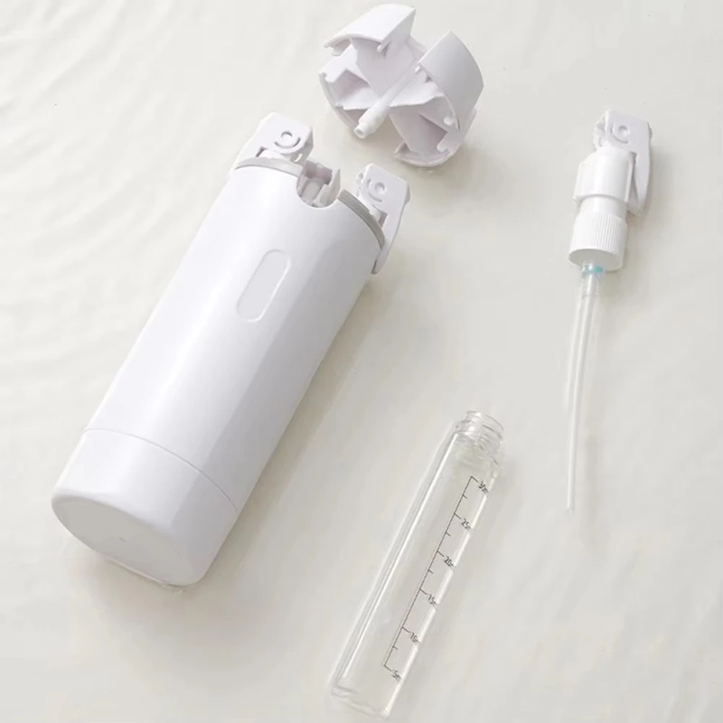 The white Fourfold Decant 4 case lying on its side, with a refill bottle, a pump and the four-way cap beside it