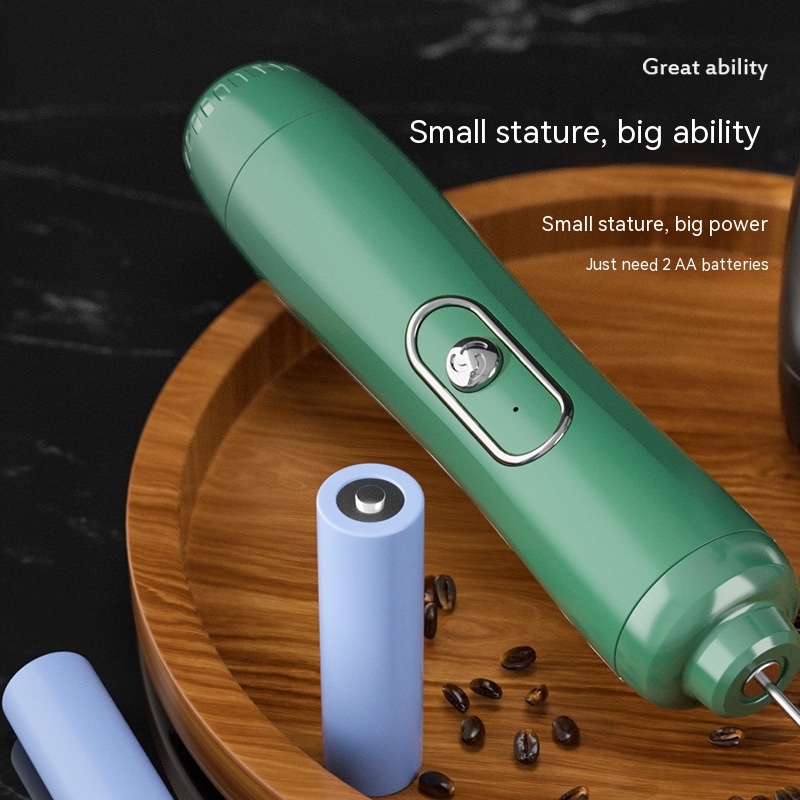 The green Fourfold Froth 3 lying on a wooden board next to two AA batteries